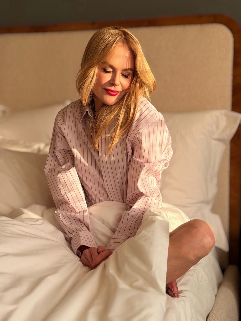 instagram photo of nicole kidman sitting on a bed in striped pink shirt with eyes closed