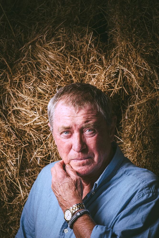 John Nettles stands in front of a wall of hay