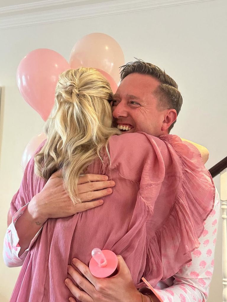 Poppy Delevingne shares a joyful hug in her Monsoon baby shower dress, surrounded by pink balloons and love. The moment captures the warmth and excitement of her celebration in full bloom.