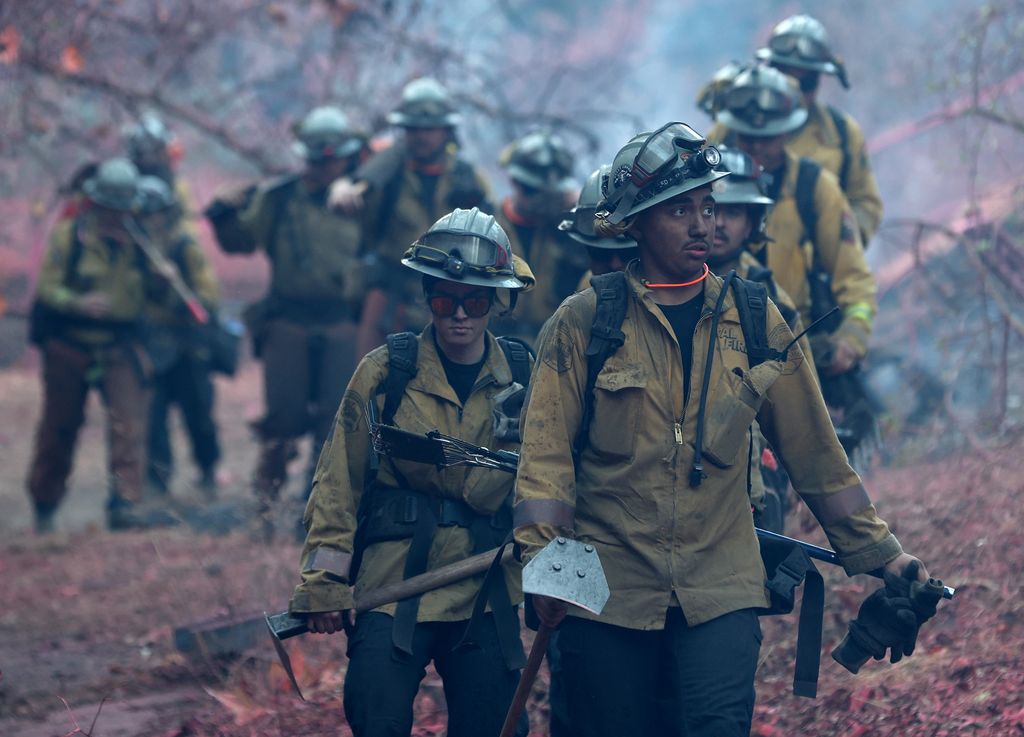 Firefighters walk down a hill as they battle the Palisades Fire on January 10, 2025 in Los Angeles, California