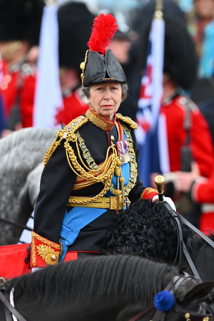 Princess Anne rides on horseback behind the gold state coach