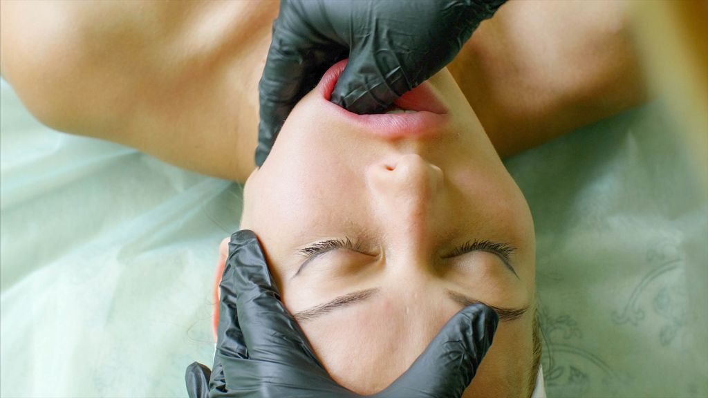 Massage therapist in gloves performing a facial buccal massage