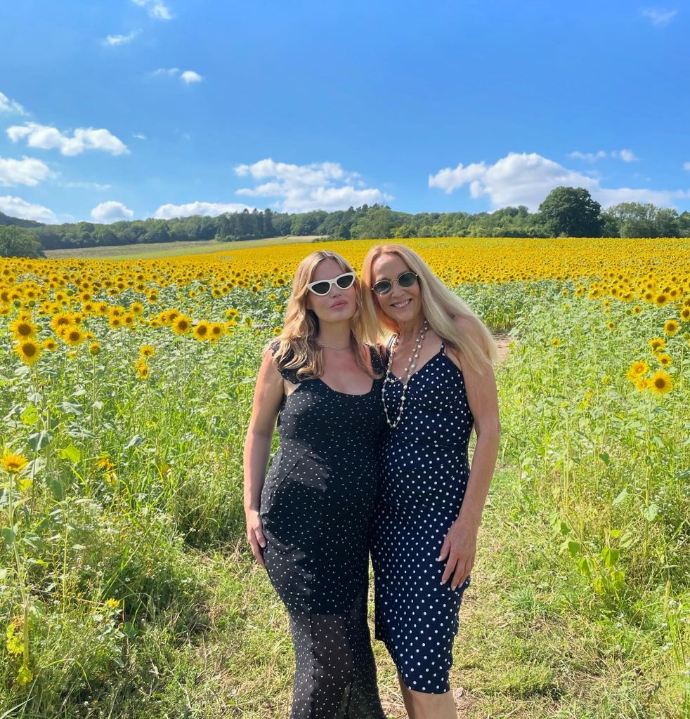 mother and daughter posing in field of sunflowers 