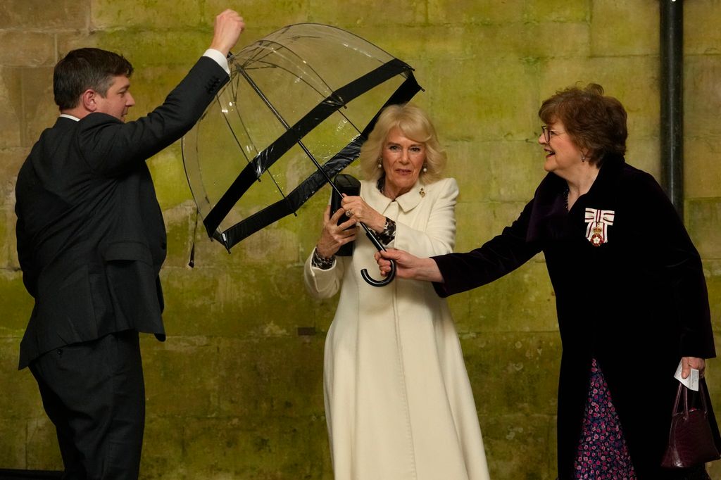 Queen Camilla hands her umbrella to an aide as she arrives to a Musical Evening at Salisbury Cathedral 