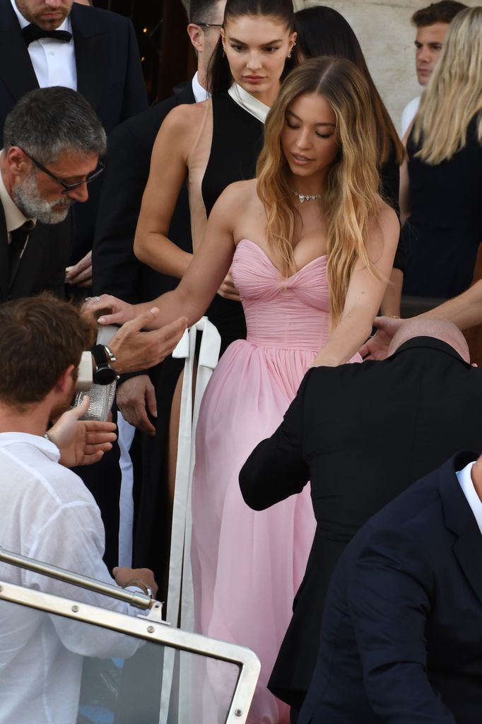 Sydney Sweeney wore a strapless pink gown with a corseted bodice and diamond necklace as she arrived by boat at the Bezos wedding