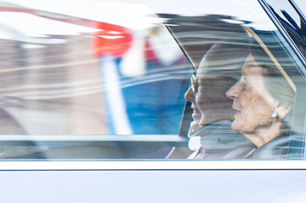 Queen Margrethe riding in the back of a car in a neck brace