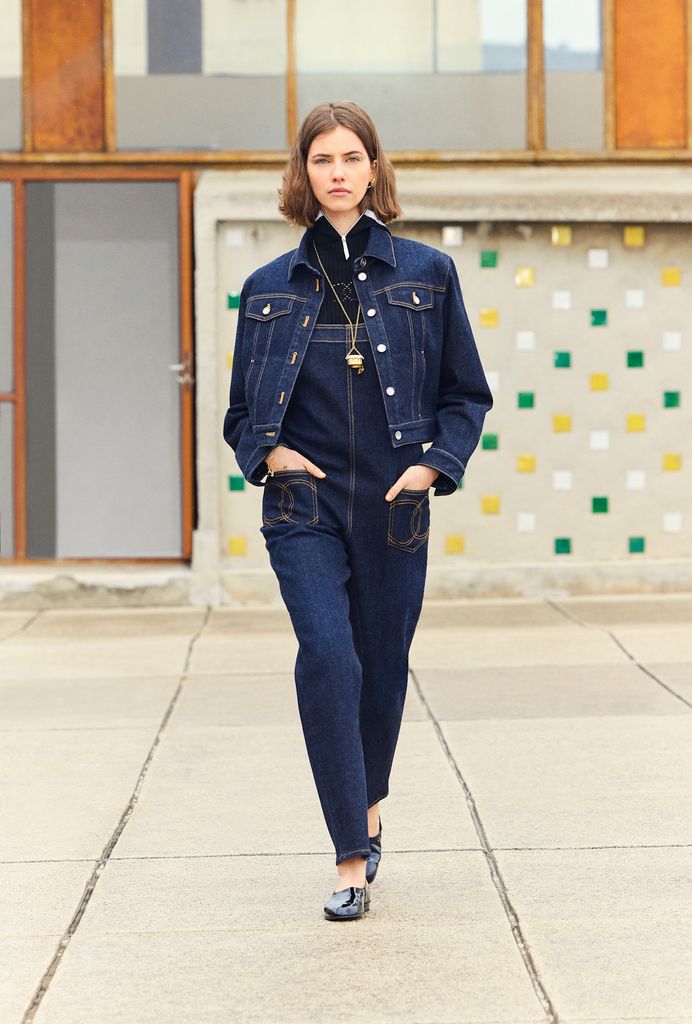 A model wears a denim jacket, denim dungarees and walks down the runway at Chanel