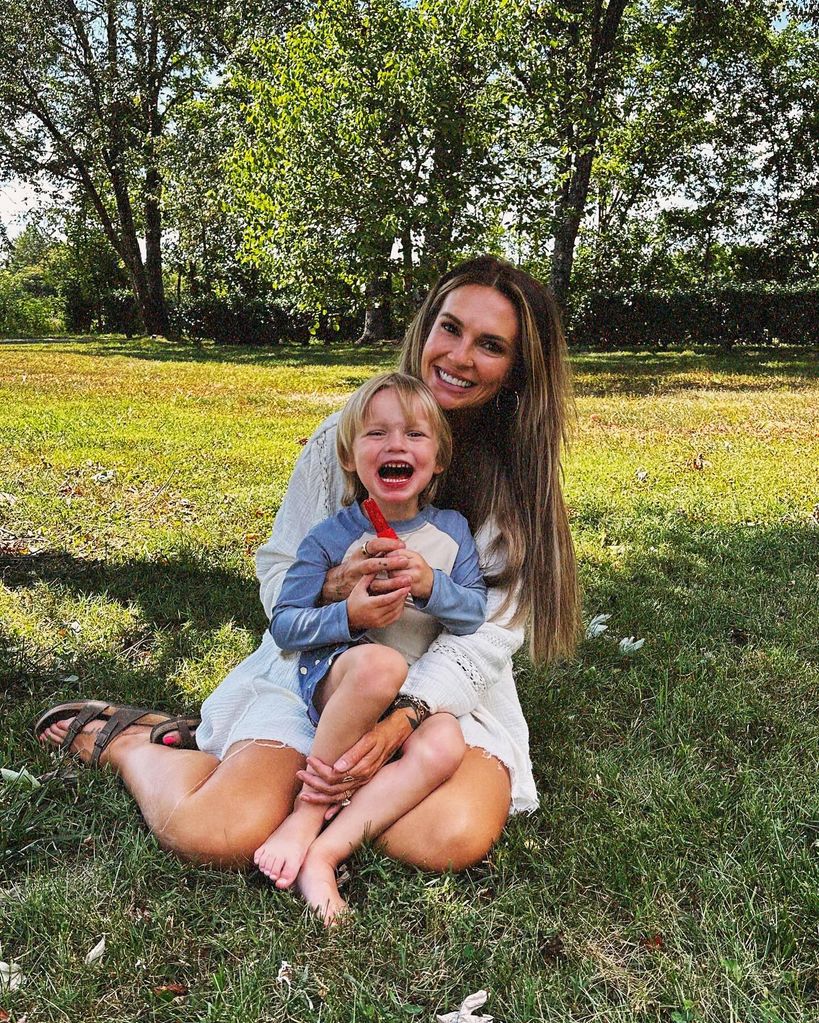 Woman hugging a young boy while sitting on the grass