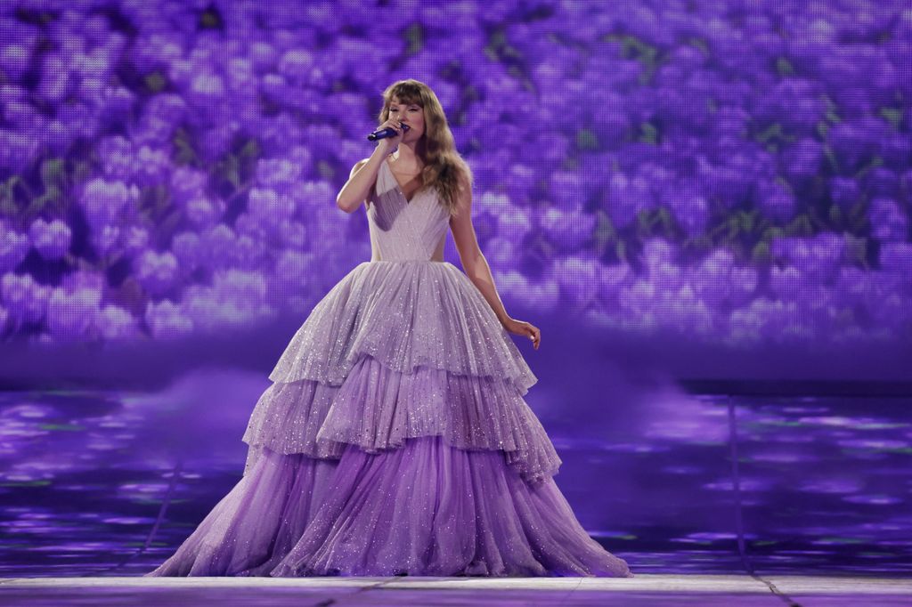 Taylor on stage wearing purple ballgown and singing into a mic