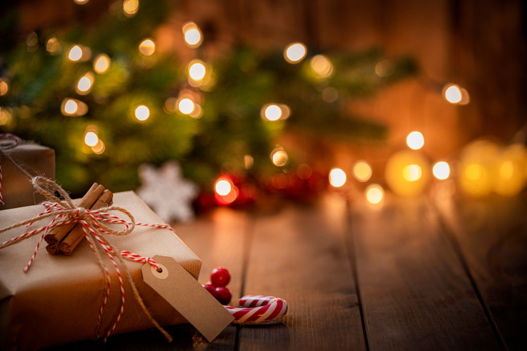 Brown Christmas gift box with a blank tag on rustic wooden table.