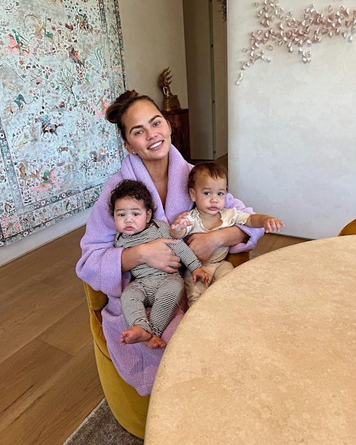 Chrissy at home in front of stunning tapestry with kids on lap
