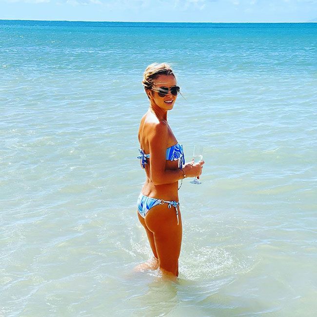 amanda stands knee deep in water wearing a blue bikini