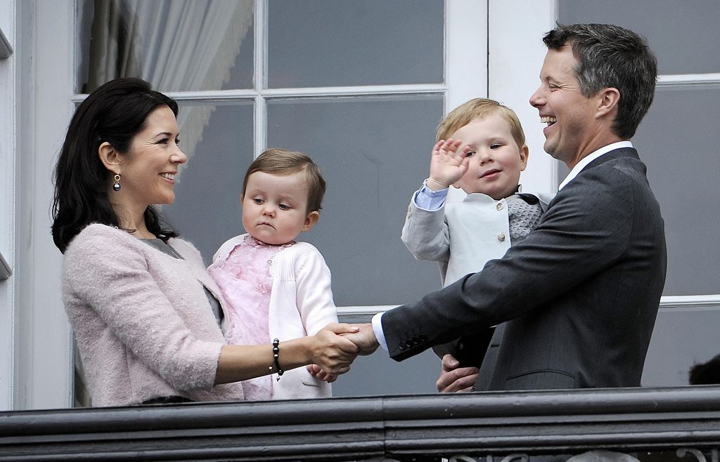 Mary and Frederik hold hands as they hold Christian and Isabella on balcony