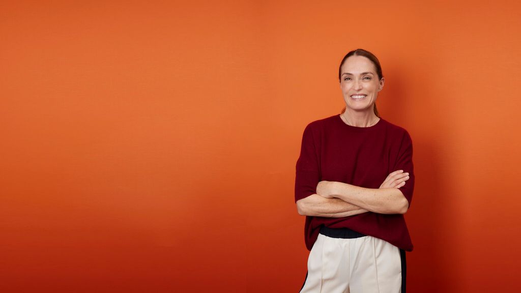 Woman in burgundy smiling on an orange background 