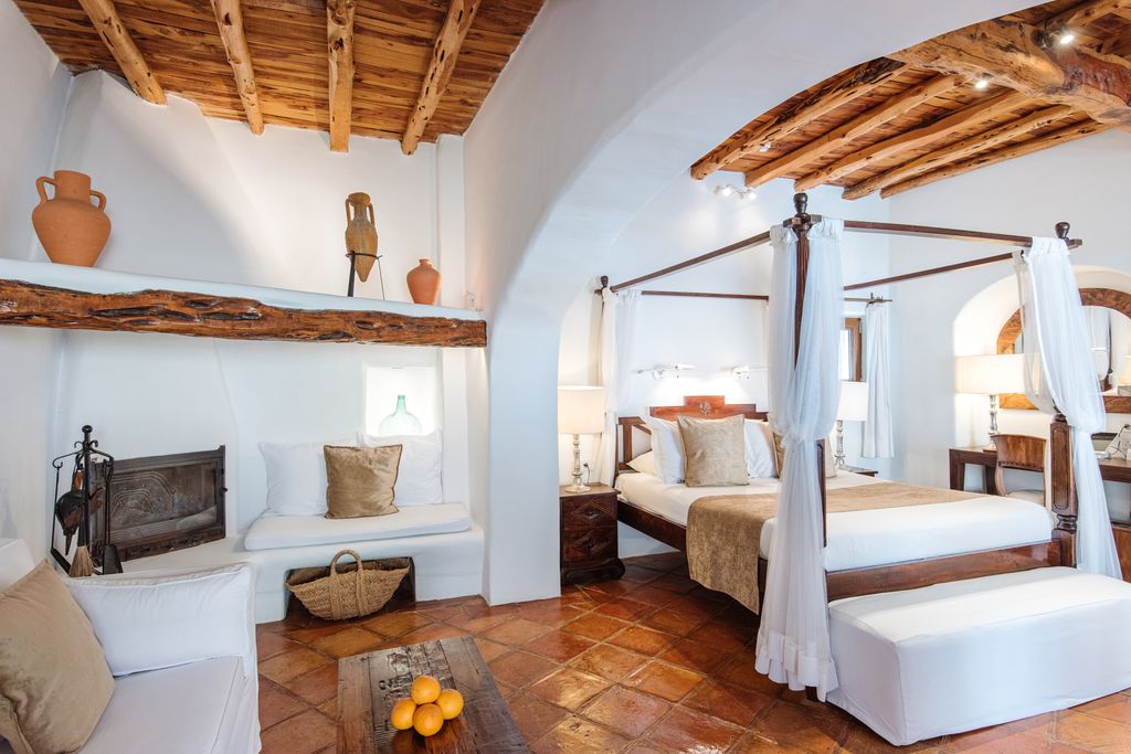 Ibiza’s Atzaró Agroturismo Hotel bedroom with white walls wooden beam ceiling and stone floors
