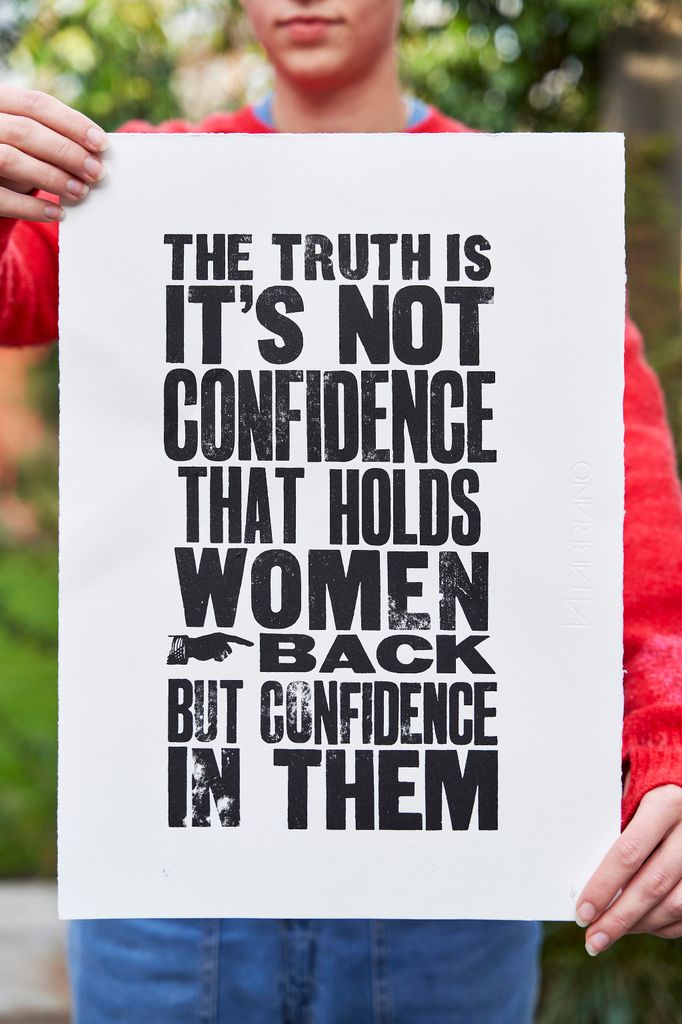 woman holding up a poster with black writing on 