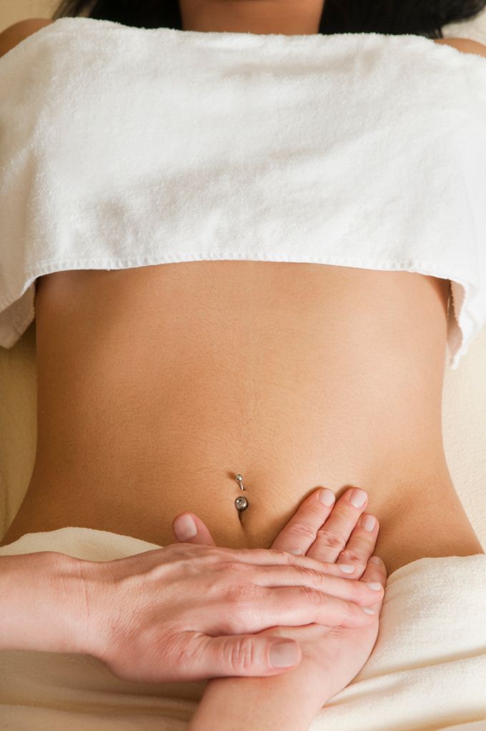 Woman receiving lymphatic massage on her abdomen.