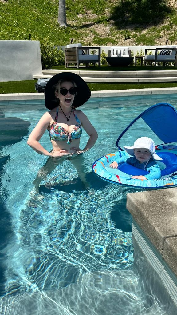 Kelly Osbourne stands in the pool with her son