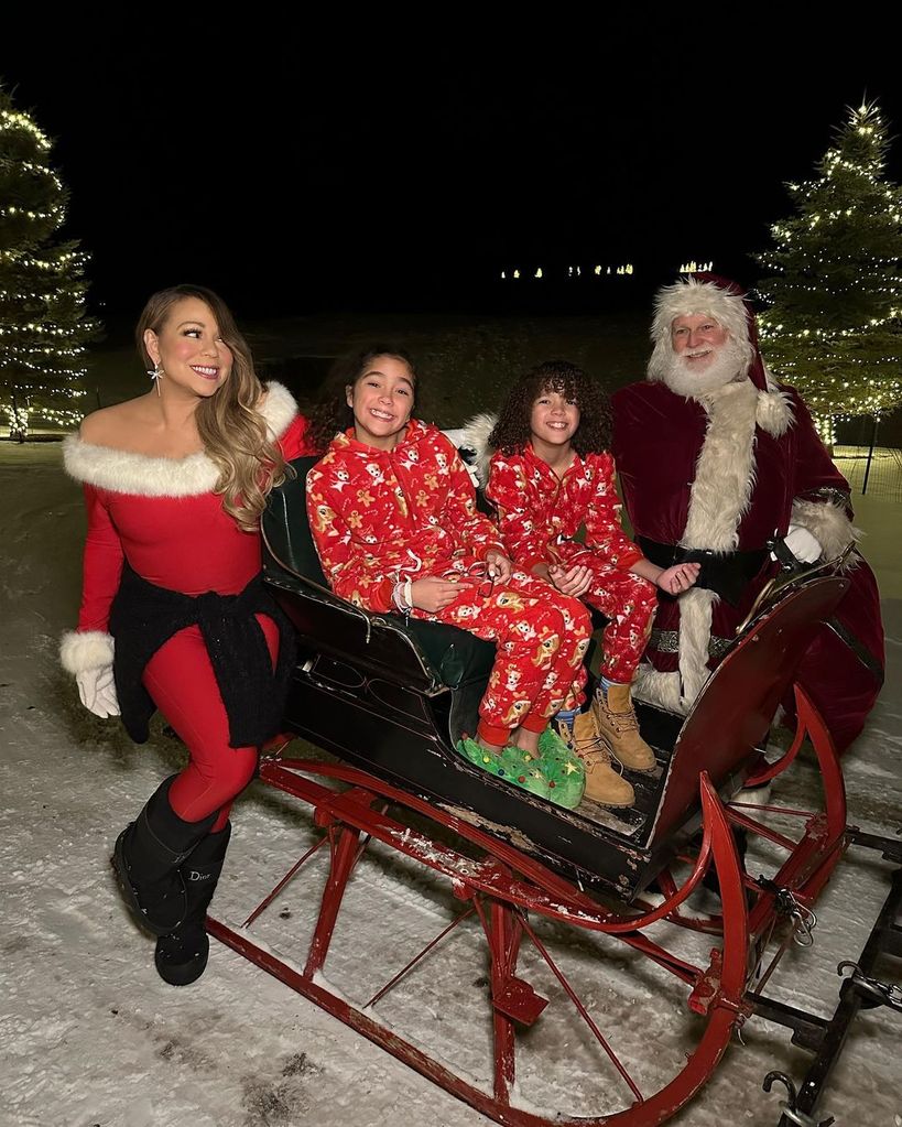 mariah carey in christmas onesie posing with twins monroe and moroccan in christmas sleigh