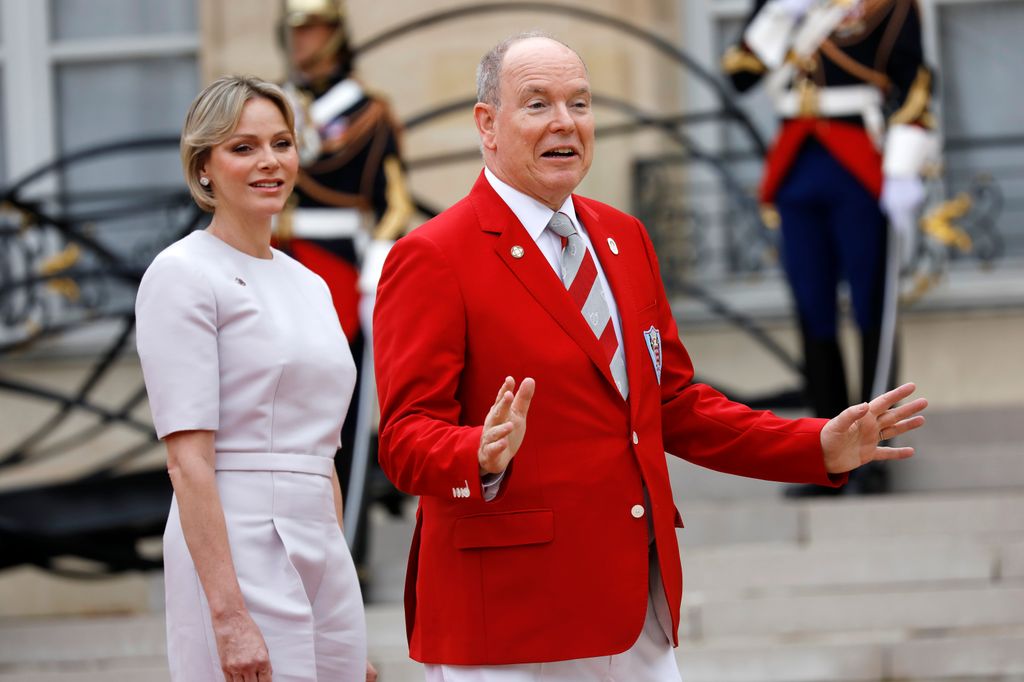 Princess Charlene in a white dress and Prince Albert in a red jacket