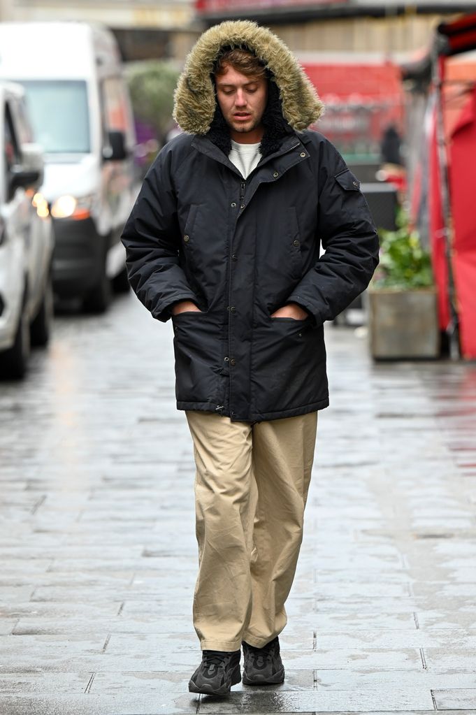 Roman Kemp walking in a black hooded coat