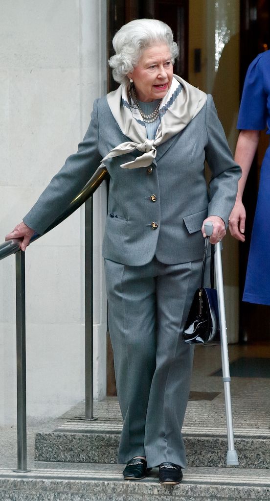 Queen Elizabeth II, seen using a crutch, leaves the King Edward VII Hospital after undergoing knee surgery in January 2003
