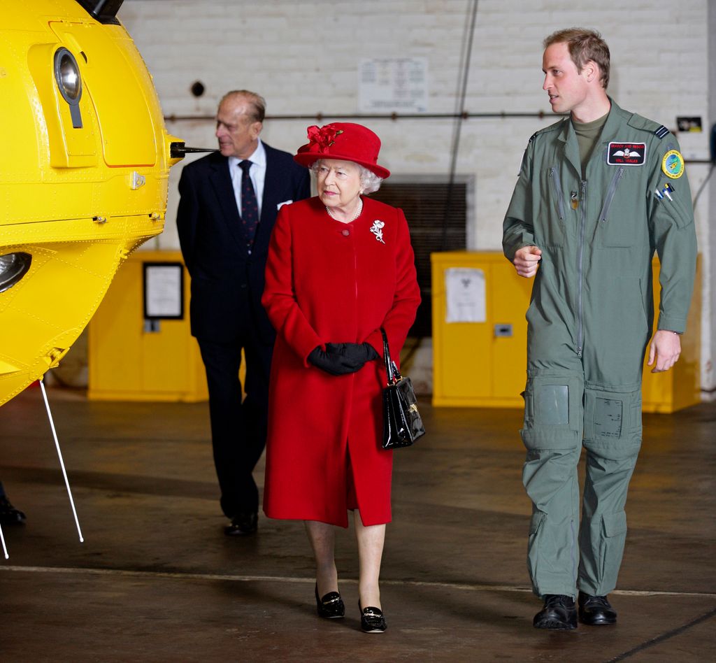 Prince William shows his grandmother Queen Elizabeth II around a Sea King search and rescue helicopter as she visits RAF Valley in 2011