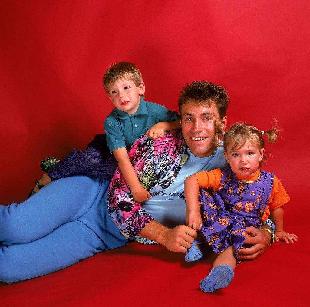 Patt Cash and two of his young children posing in front of a red background
