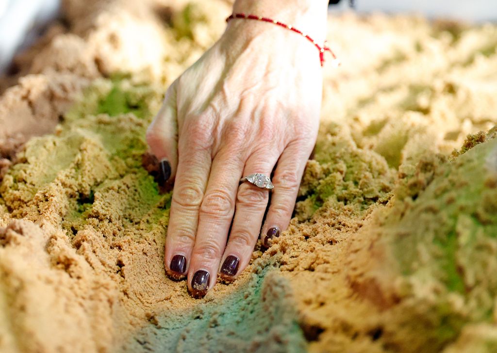 Tangan Sophie dengan cincin berlian di pasir