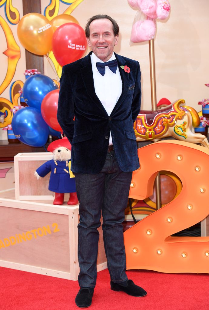 Ben Miller standing for photos in front of bright balloons and toys at the Paddington 2 premiere