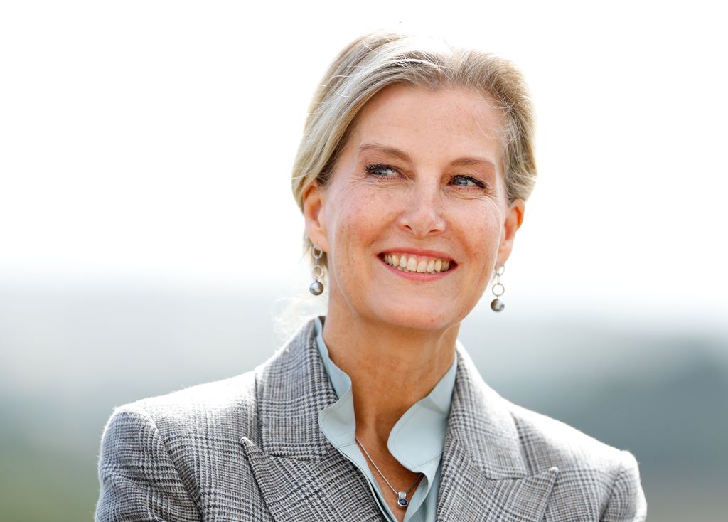 The Duchess of Edinburgh smiling and wearing check blazer, pastel blouse and silver jewellery 