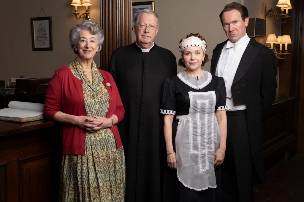 Four people stand in a room in period outfits. Maureen Lipman, Mark Williams, Julia Sawalha and Alex Maqueen in Father Brown