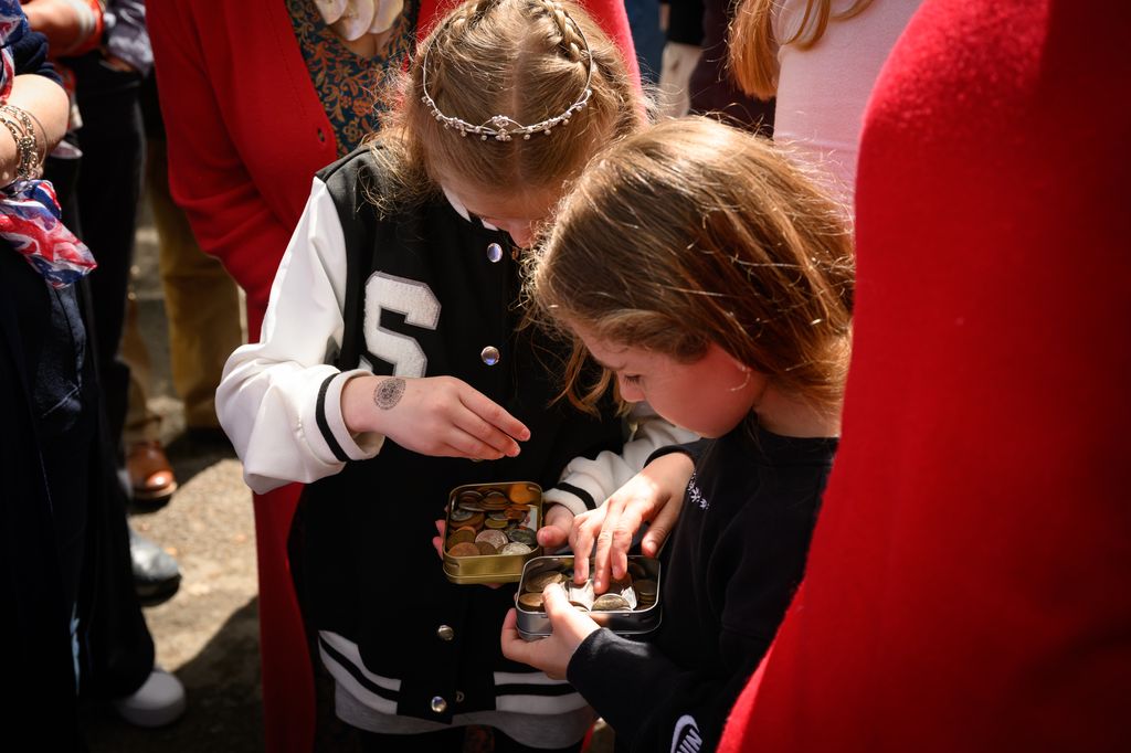 Children view the contents of their commemorative tin after being presented them by Princess Anne during her visit to a Coronation street party in Swindon
