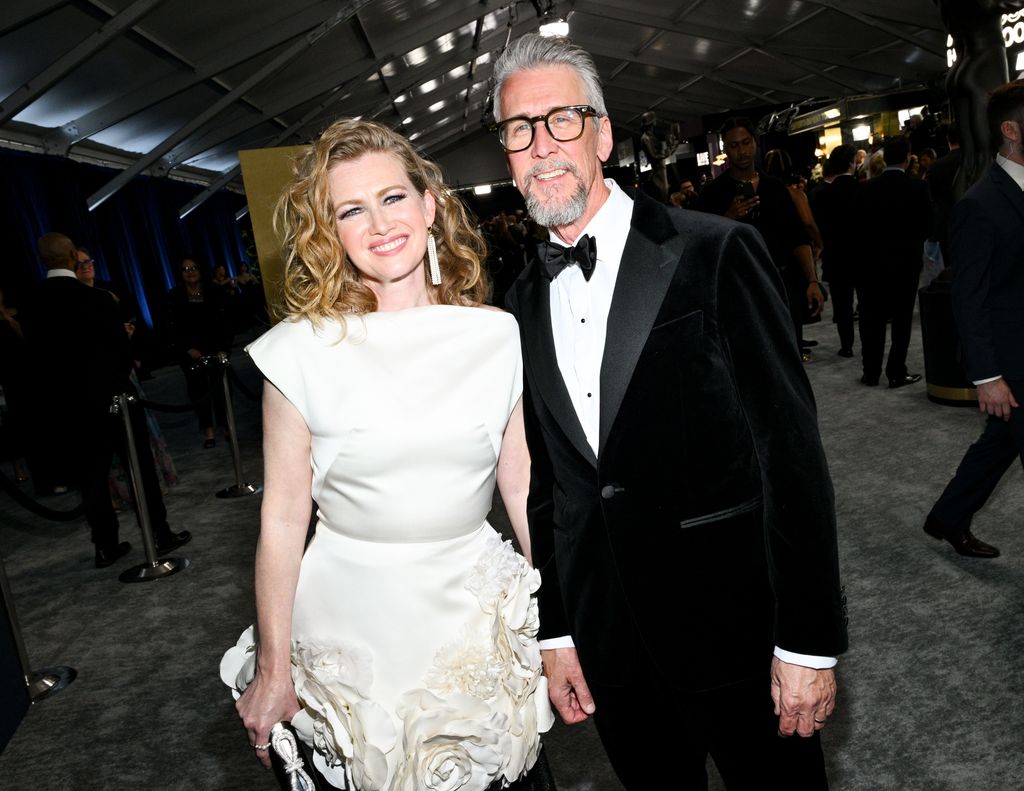 Mireille Enos in a white dress and Alan Ruck in a velvet jacket