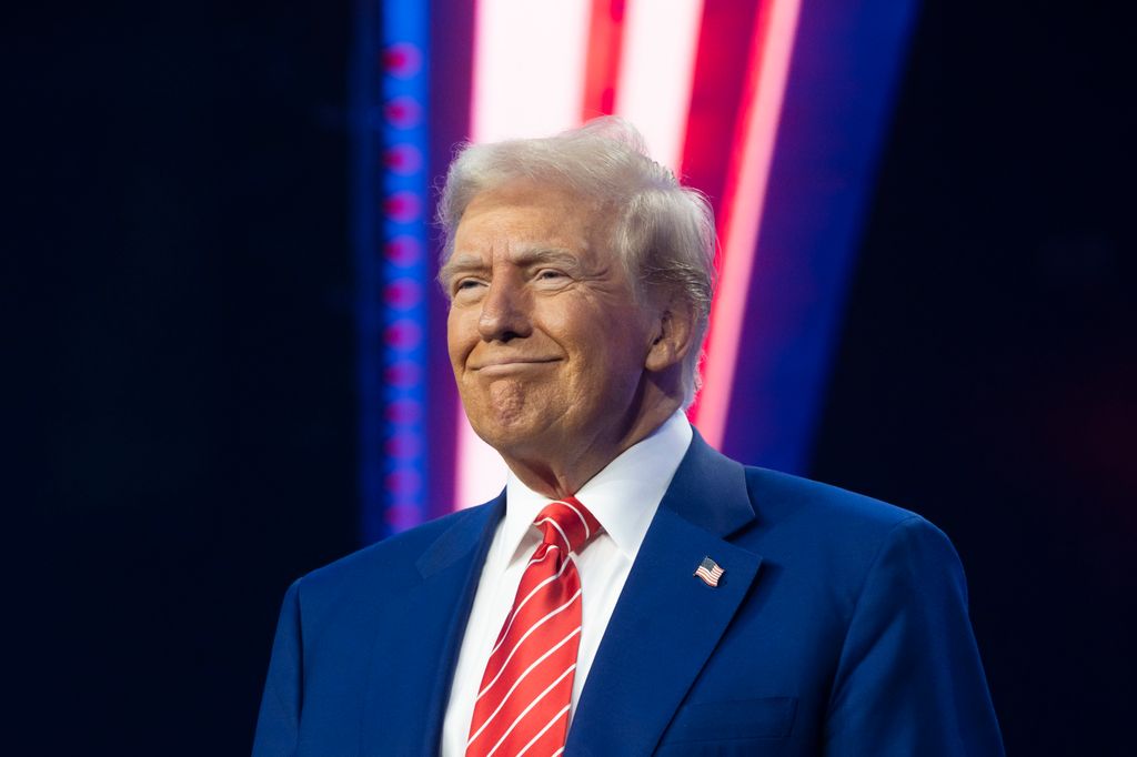 Smiling Donald Trump in blue suit and orange tie with white slanted stripes