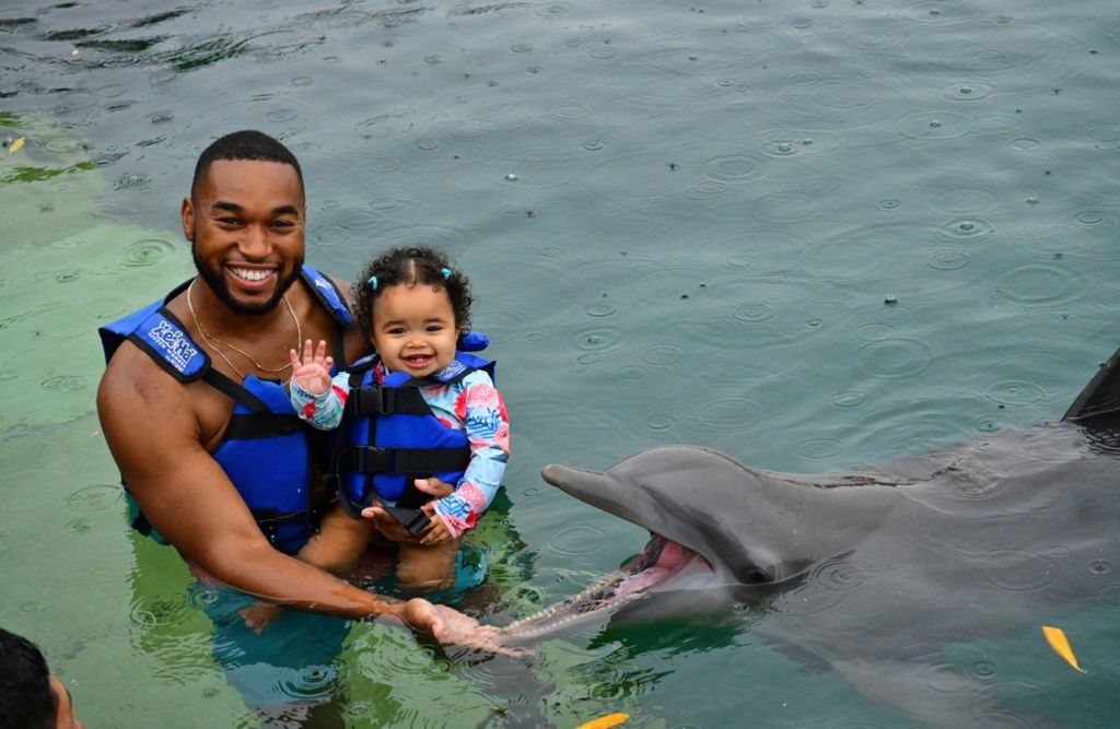 Tye White and his youngest Asaanah swim with dolphins
