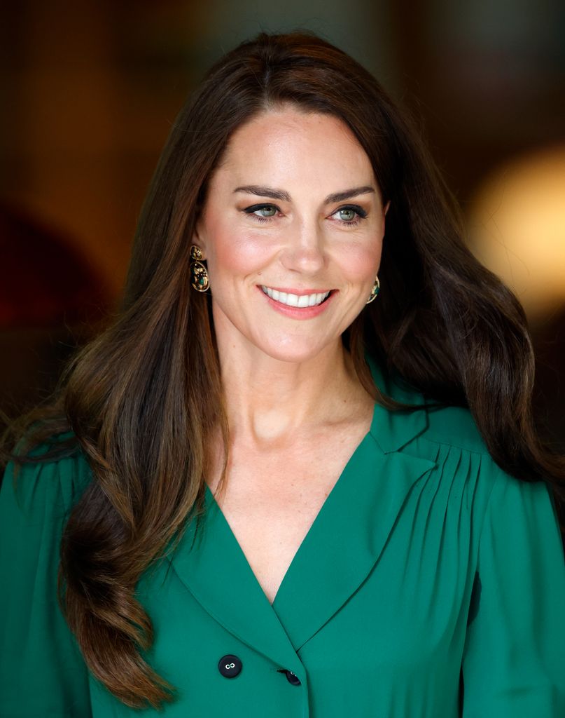 Kate Middleton usando vestido verde e sorrindo