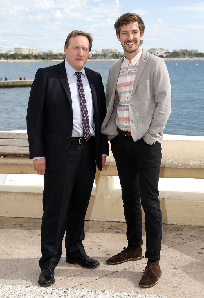 two men smiling in front of sea backdrop