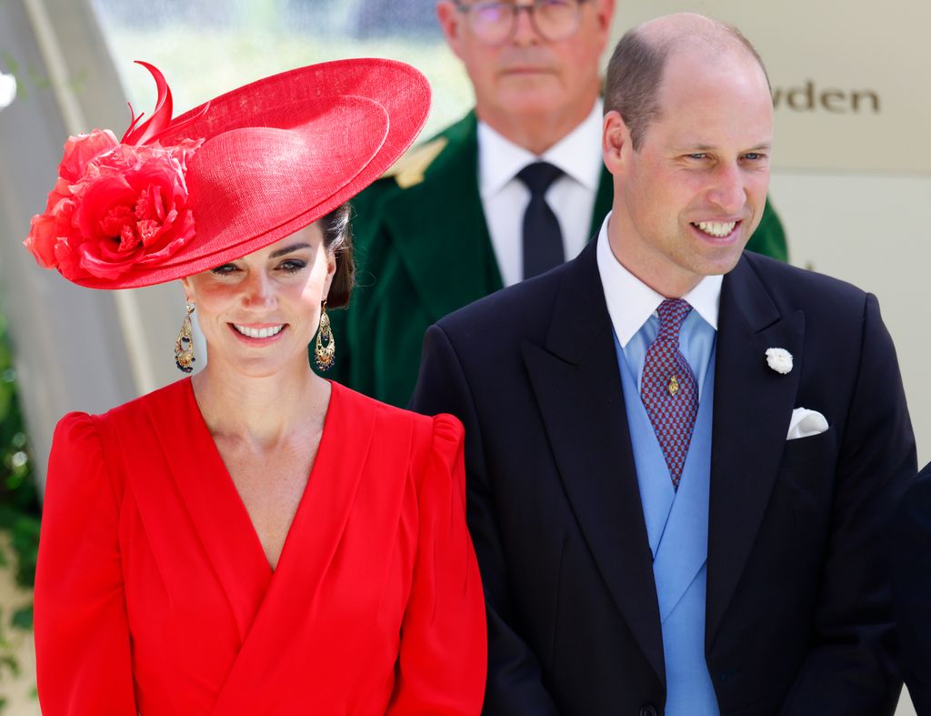 Kate Middleton in a red outfit and Prince William in a black suit