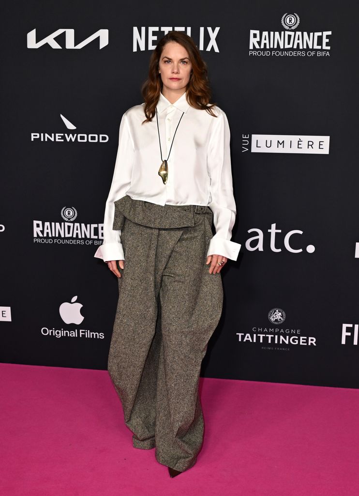 Ruth Wilson on pink carpet in white shirt and tweed trousers