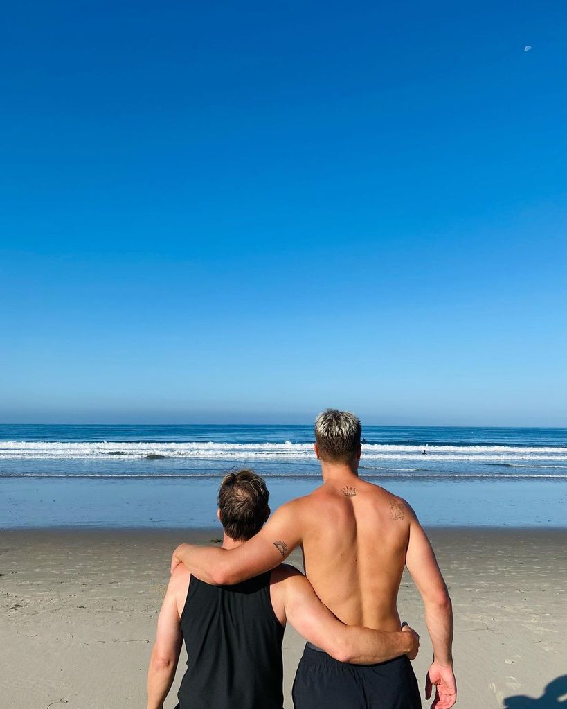 Gary Barlow with arm around his son, Daniel, on a beach