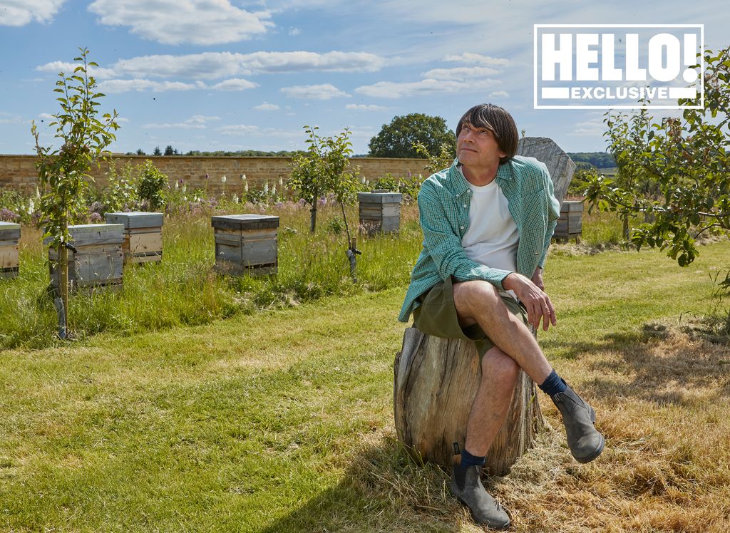 Blur star Alex James posing on tree trunk in field at farmhouse in Kingham, Oxfordshire 