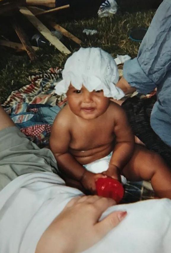 Maya Jama as a baby wearing a baby bonnet