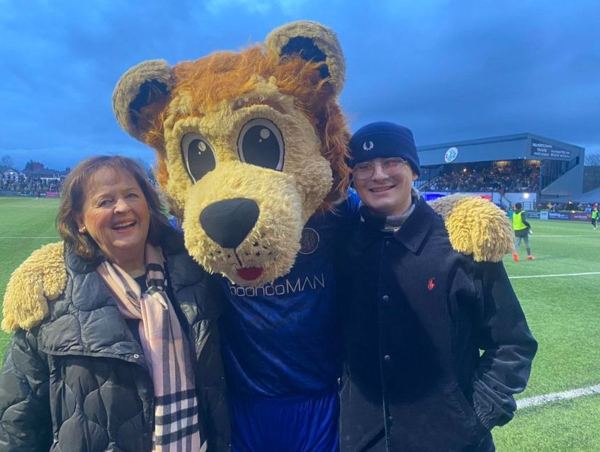 Margie Cooper with a male family member and a football mascot