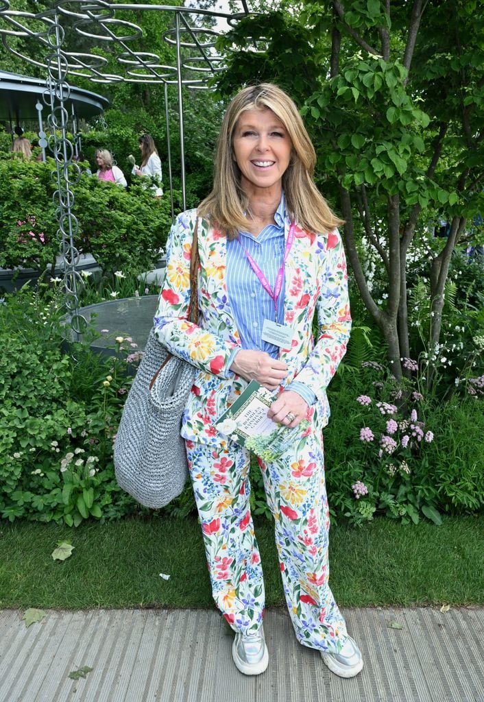 Kate Garraway in a colourful floral suit and striped shirt with silver trainers at Chelsea Flower Show, carrying a grey knitted bag.