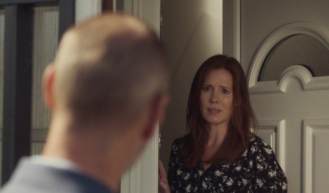 Woman with red hair standing in front of door looking at a man