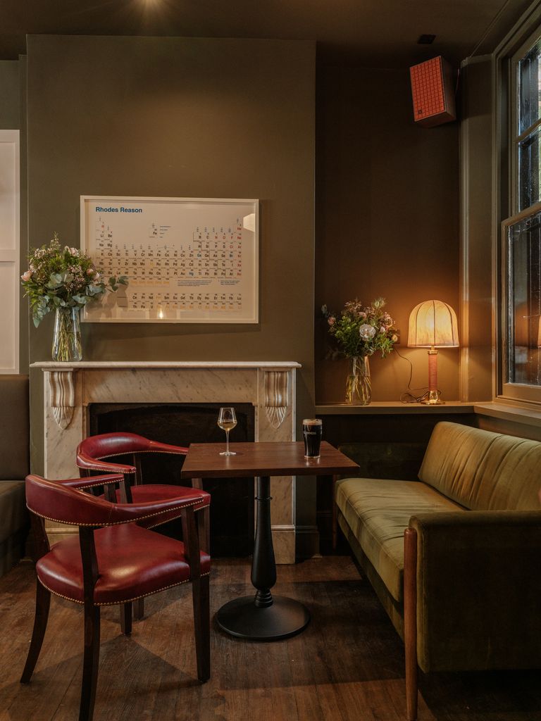 A green sofa and red chairs inside a pub