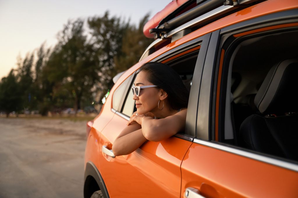 woman leaning out of car window while on a road trip