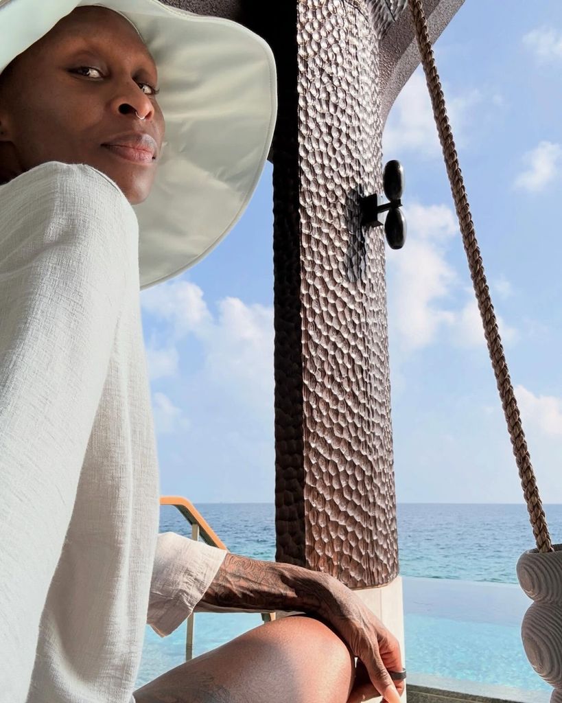 cynthia erivo in sunhat with sea in backdrop