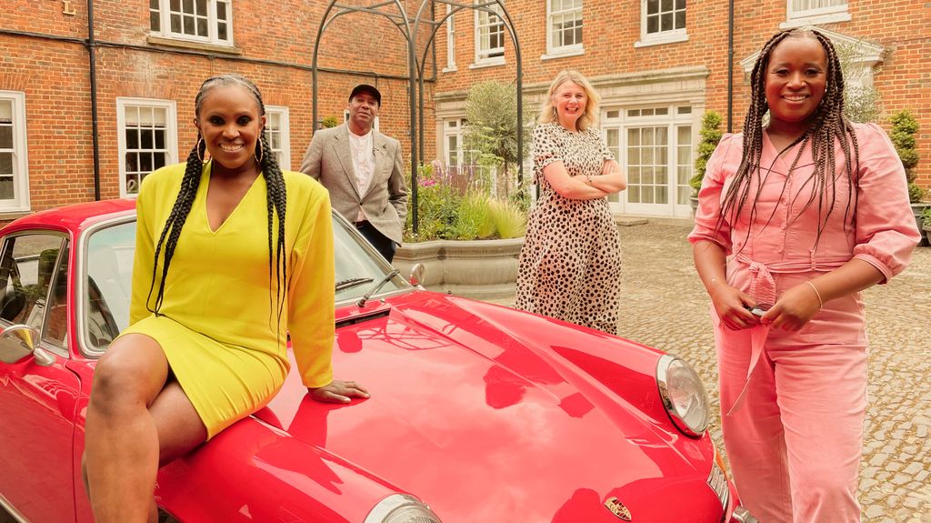 group of people standing beside red car